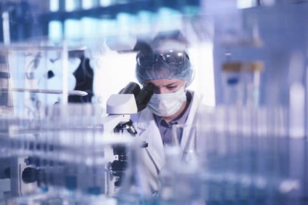 Female microbiologist studying coronavirus with microscope. Fighting with pandemic